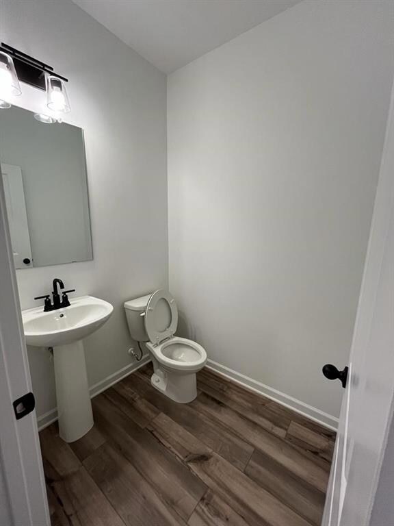 Half bath on main floor featuring toilet and wood finished floors