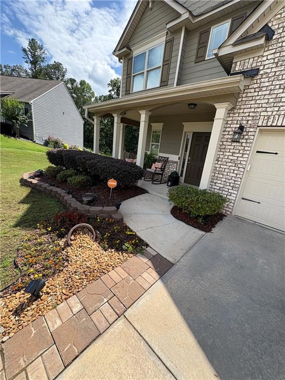 Property entrance featuring a porch, a yard, and a garage