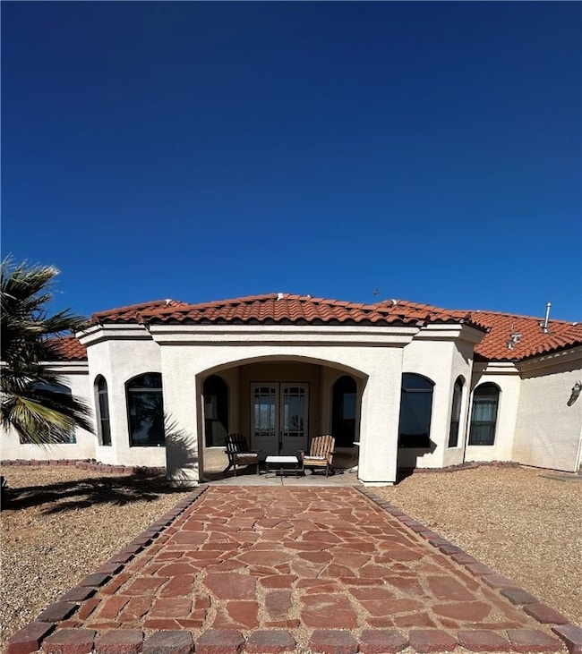 Rear view of house featuring french doors, stucco siding, and a tile roof