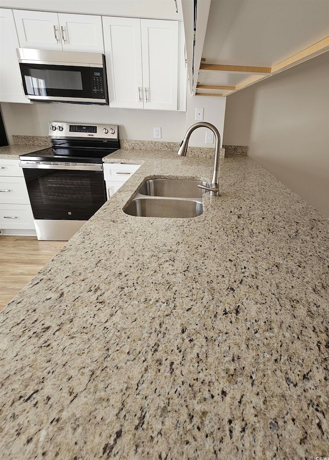 Kitchen with white cabinetry, light stone countert