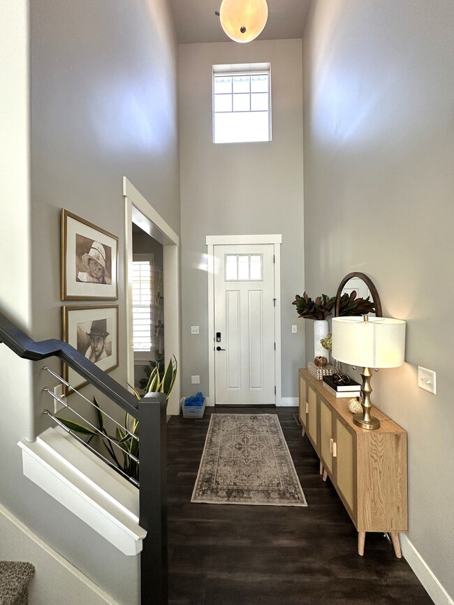 Entrance foyer with healthy amount of natural light, a high ceiling, and dark wood-style flooring