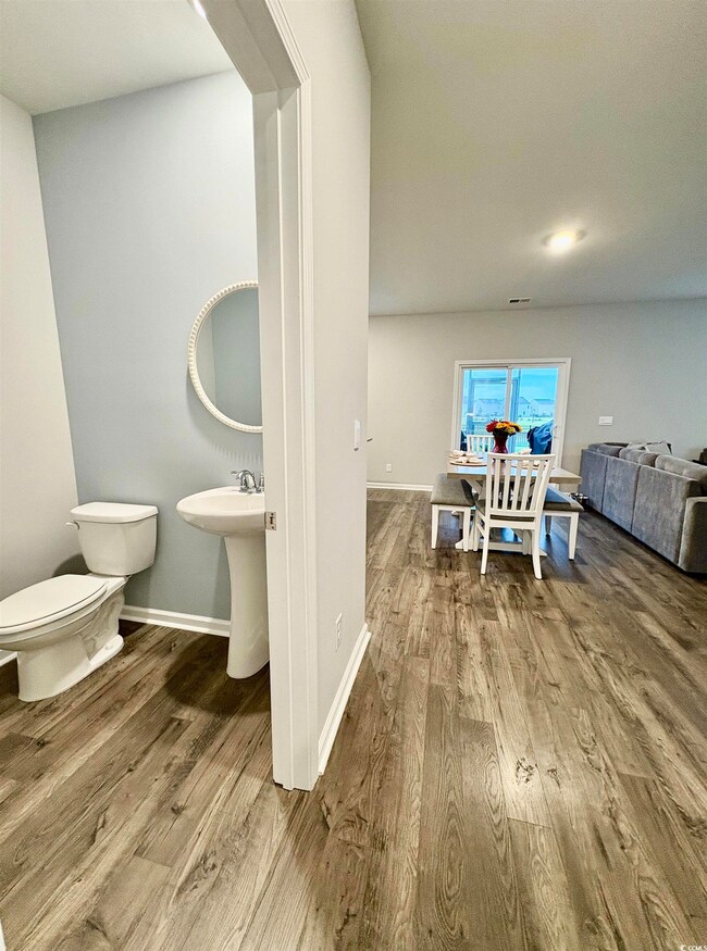 Half bath with toilet, wood finished floors, and baseboards