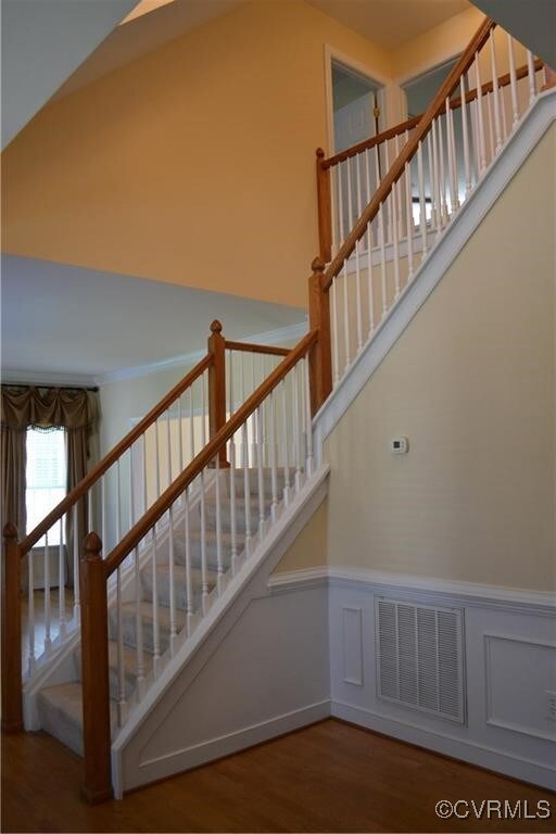 Stairs with a wainscoted wall, wood finished floor