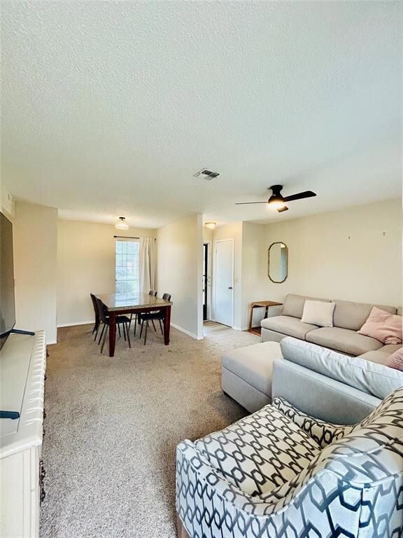 Carpeted living area featuring a ceiling fan