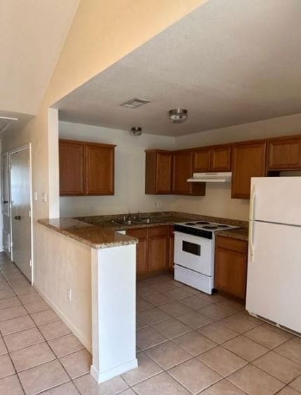 Kitchen with white appliances, light tile patterne