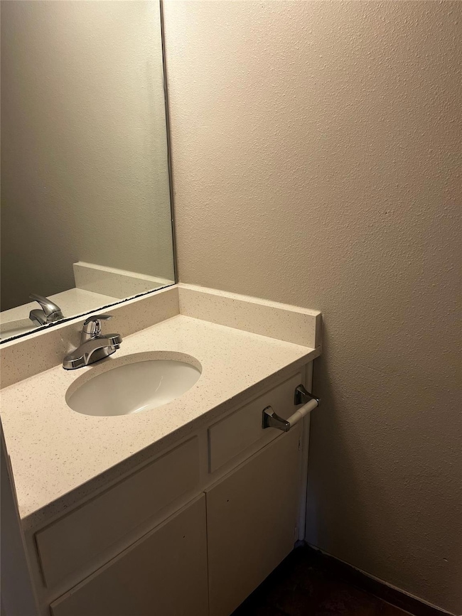 Bathroom featuring a textured wall and vanity