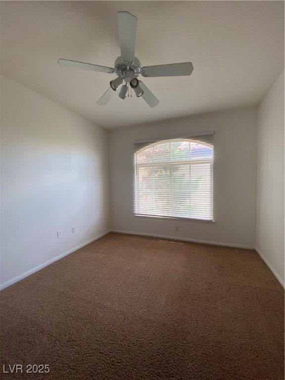 Carpeted empty room featuring baseboards and ceiling fan
