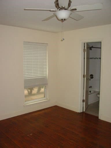 Unfurnished bedroom with dark wood-style flooring, a ceiling fan, and connected bathroom
