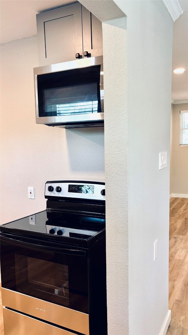 Kitchen with stainless steel appliances, wood finished floors, and crown molding