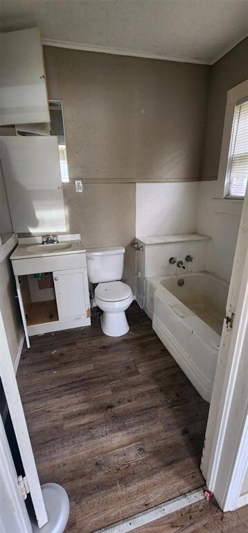 Bathroom with toilet, a bath, and hardwood / wood-