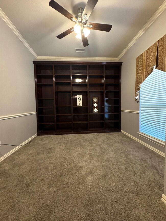 Empty room with ornamental molding, carpet floors, and a ceiling fan