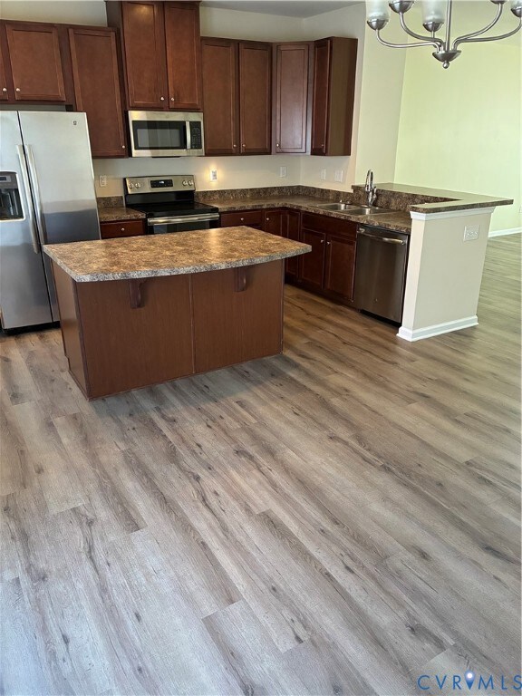 Kitchen with refrigerator, a chandelier, stainless steel range, and light wood finished floors