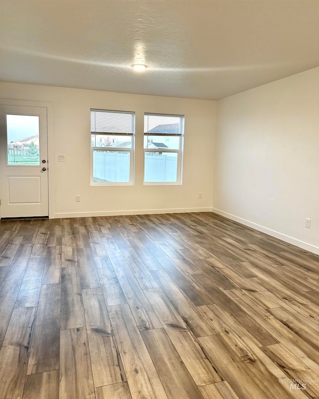 Unfurnished room with wood finished floors and baseboards