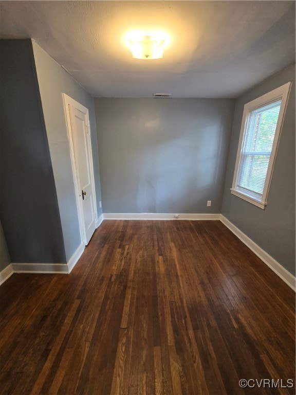 Spare room featuring dark wood-type flooring and b