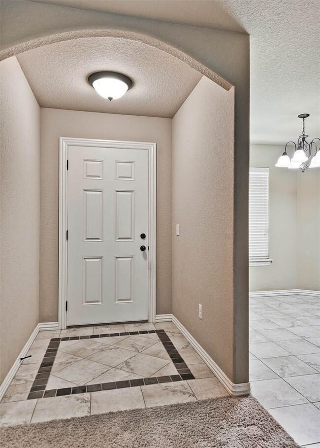 Tiled entryway with architectural design throughout the home. Arched entries, rounded corners, tiled dining room.