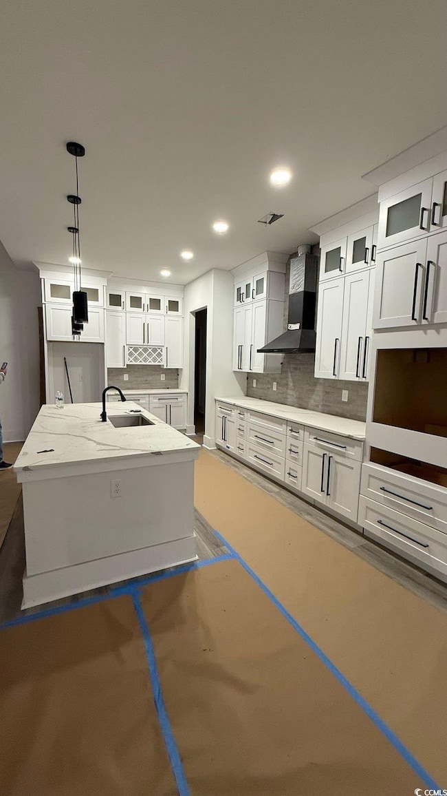 Kitchen featuring a sink, wall chimney range hood,