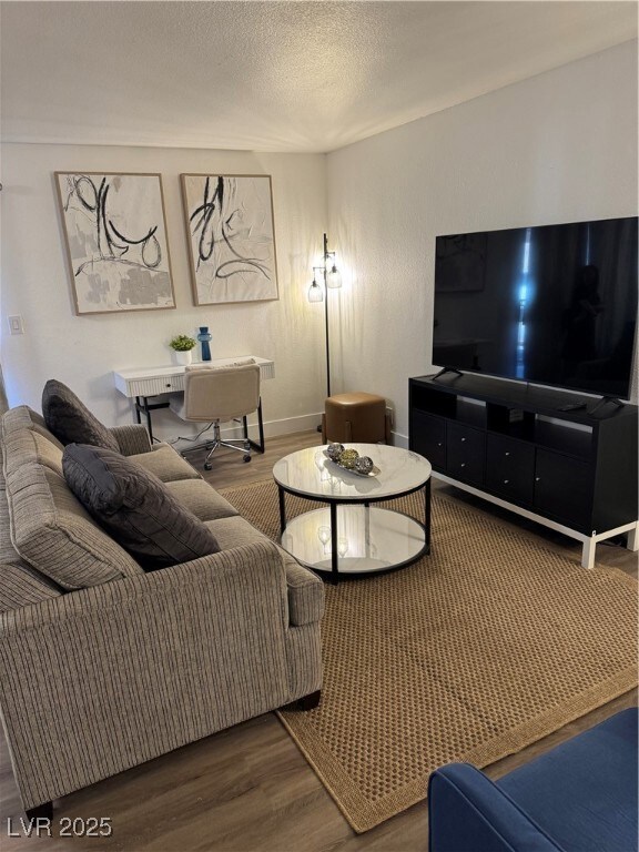 Living room featuring wood finished floors, a textured ceiling, and an office area