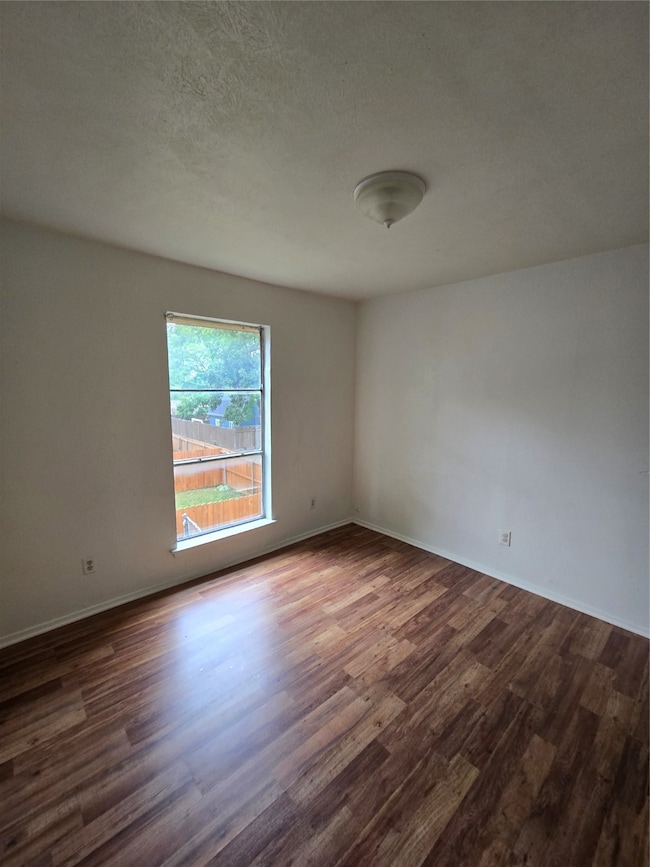 Spare room featuring dark wood-style flooring and a textured ceiling