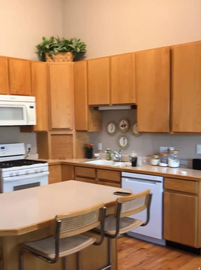 Kitchen with white appliances, light countertops, a breakfast bar, and light wood-style floors