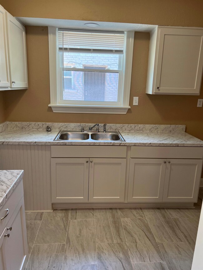 Kitchen featuring white cabinetry, a sink, and lig
