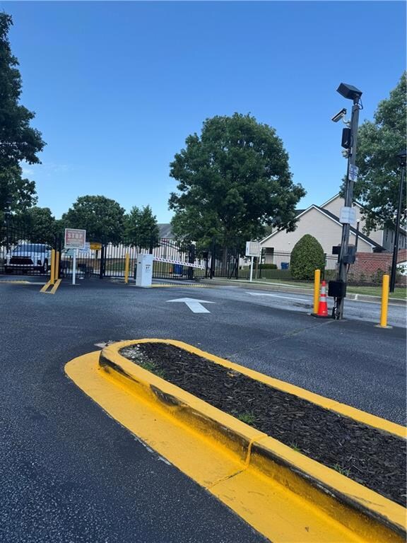 View of asphalt street with street lights, curbs, and a gated entry