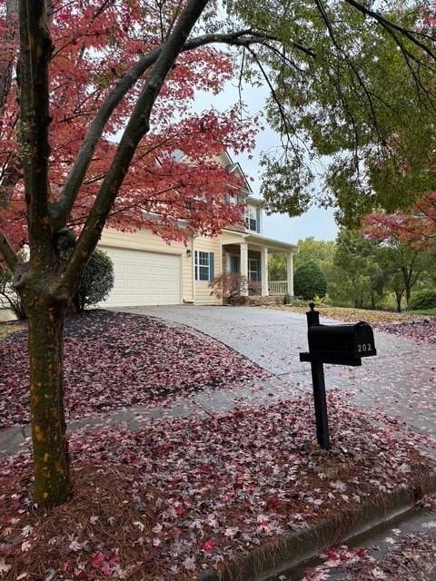 Obstructed view of property featuring a porch, concrete driveway, and an attached garage