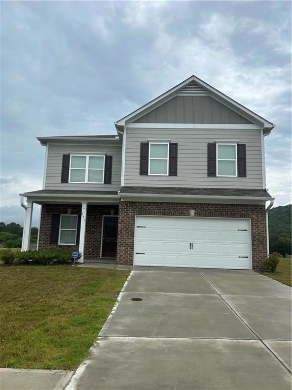 View of front facade featuring brick siding, driveway, a porch, and a garage