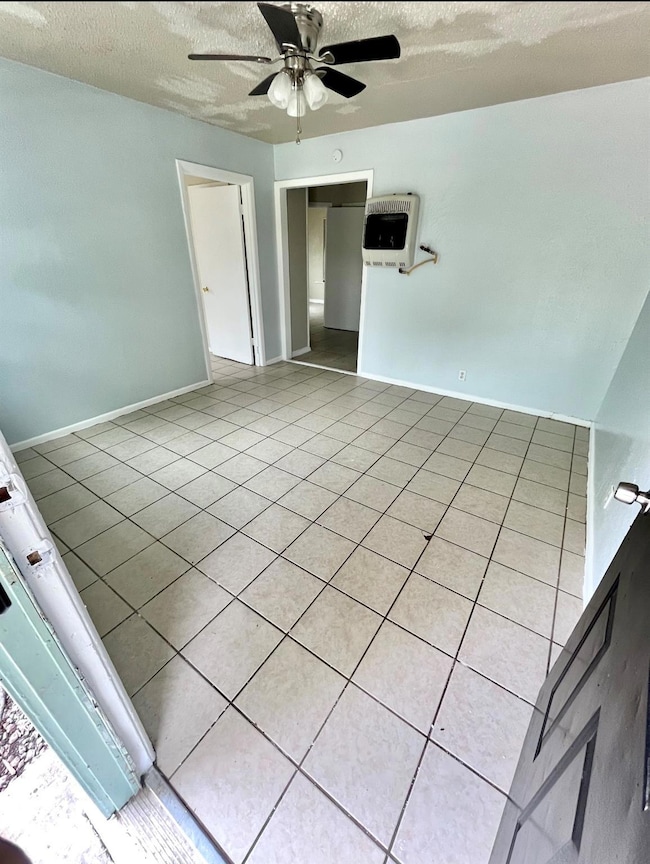 Tiled spare room with heating unit, ceiling fan, a