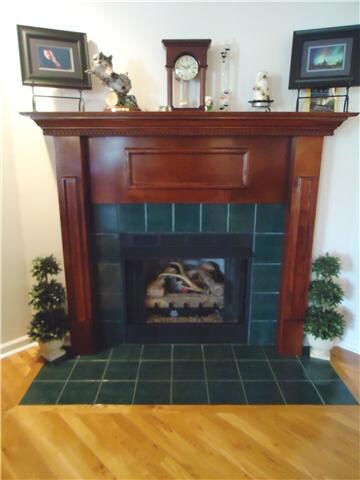 The great room features a corner English fireplace with custom wood mantel, molding and tile.   