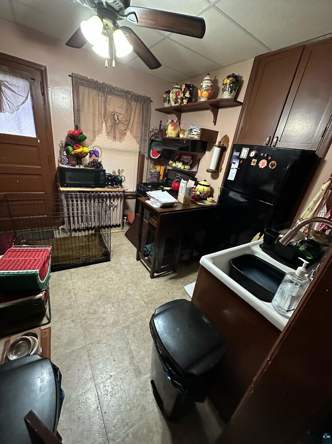 Kitchen featuring ceiling fan, open shelves, black microwave, and a sink