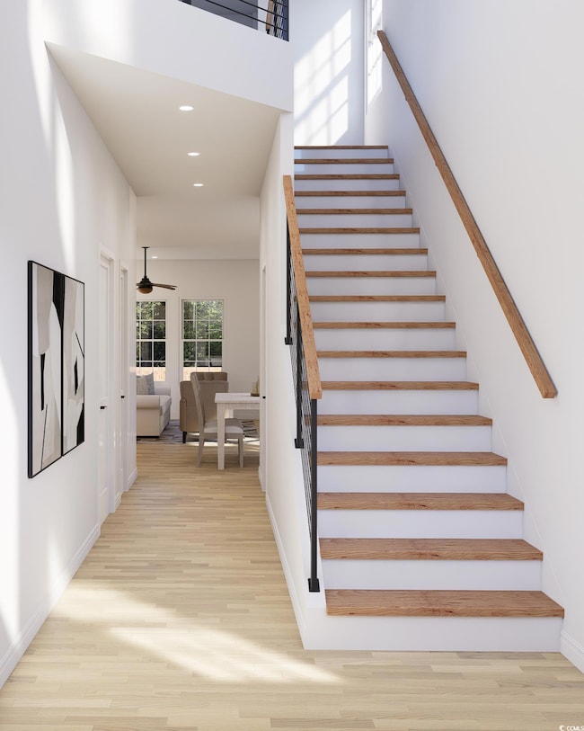Staircase with wood finished floors, a towering ceiling, and recessed lighting