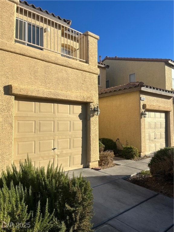 View of side of home featuring stucco siding, driveway, and a tile roof