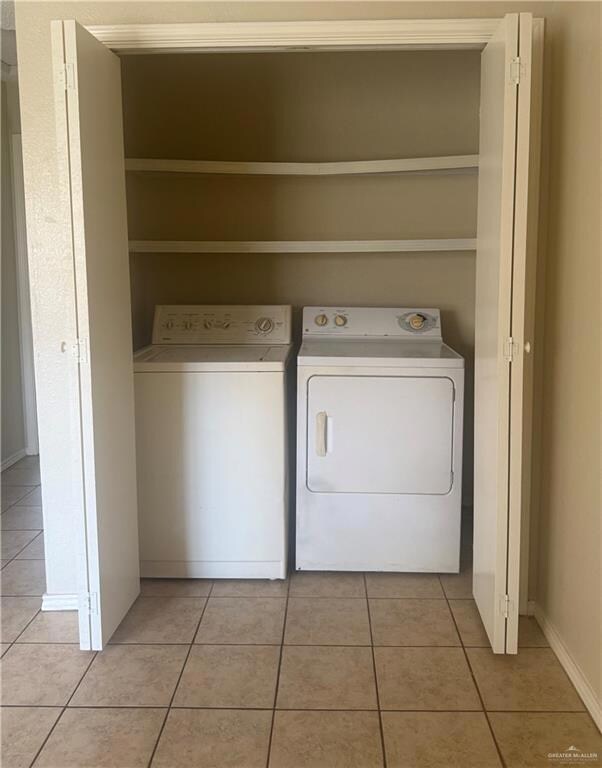 Laundry area with washing machine and clothes dryer and light tile patterned flooring