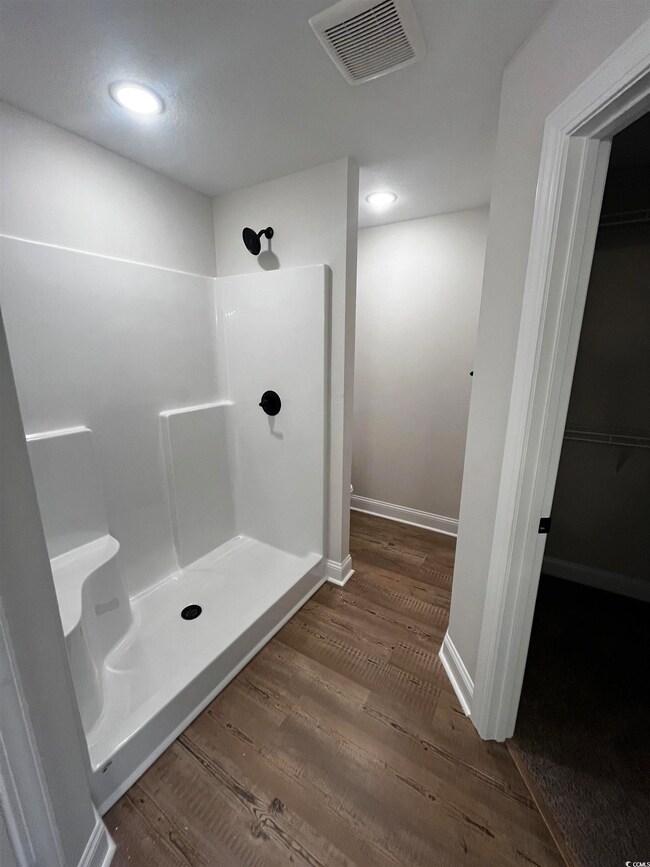 Bathroom with wood finished floors, a stall shower