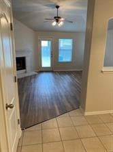Unfurnished living room featuring a fireplace, a ceiling fan, and light tile patterned floors