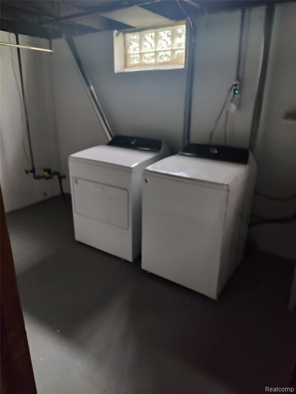 Washroom featuring finished concrete floors and washer and dryer
