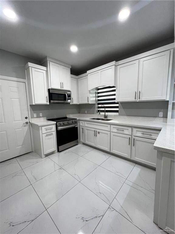 Kitchen with range, light marble finish floors, recessed lighting, and white cabinetry