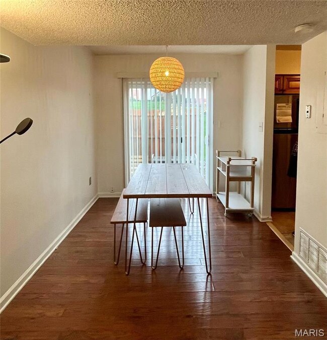 Dining room with visible vents, a textured ceiling, baseboards, and dark wood finished floors