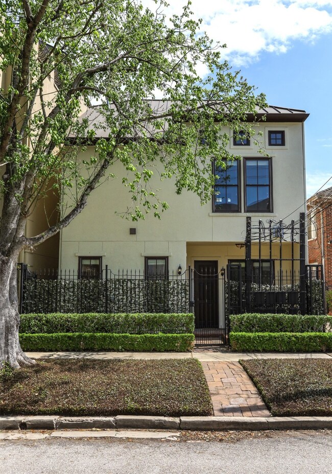 The home's private front gate faces lush, tree-lin