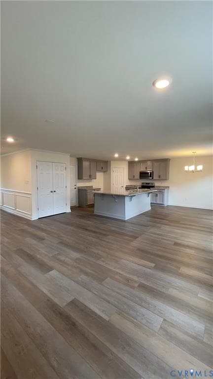 Kitchen with dark wood finished floors, open floor plan, an island with sink, gray cabinetry, and recessed lighting