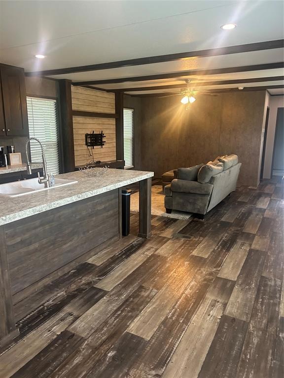 Living room featuring dark wood-style floors, ceiling fan, and wooden walls