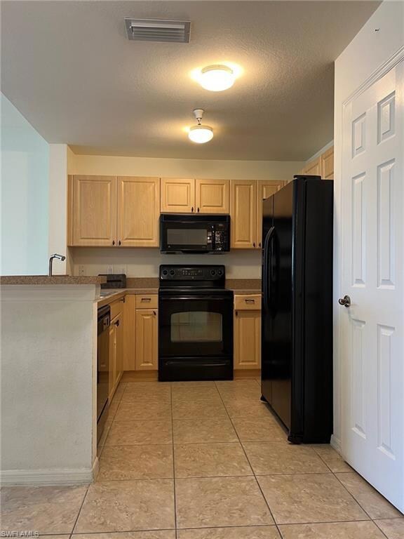 Kitchen with a textured ceiling, black appliances,