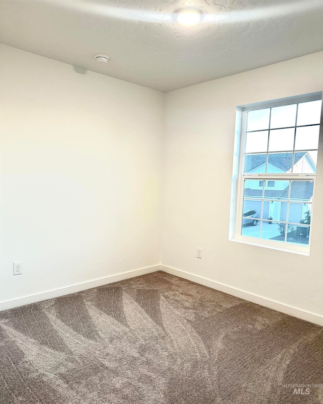 Unfurnished room featuring baseboards and dark carpet
