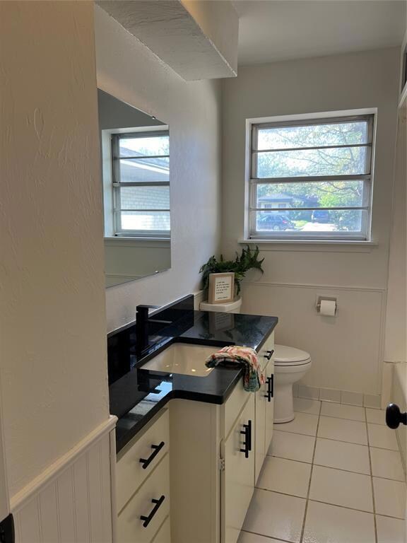 Bathroom with toilet, vanity, and tile floors