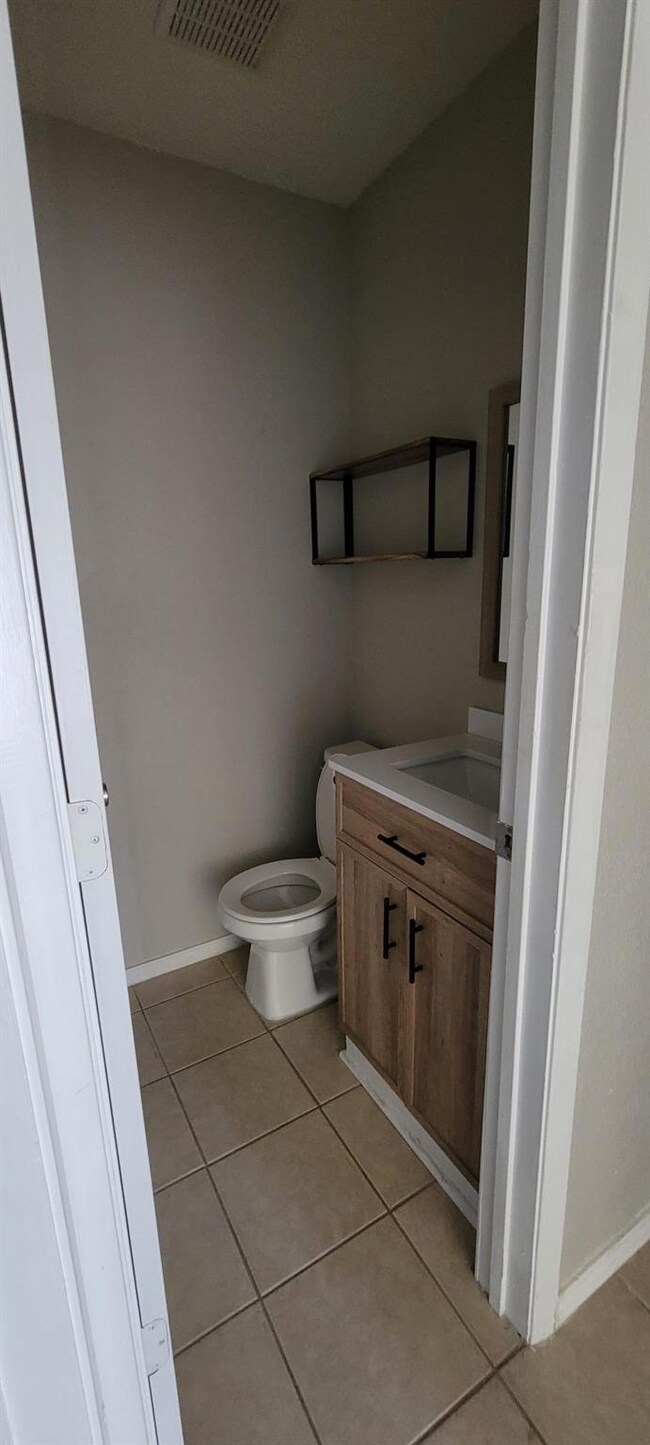 Bathroom featuring vanity, tile patterned flooring, and toilet