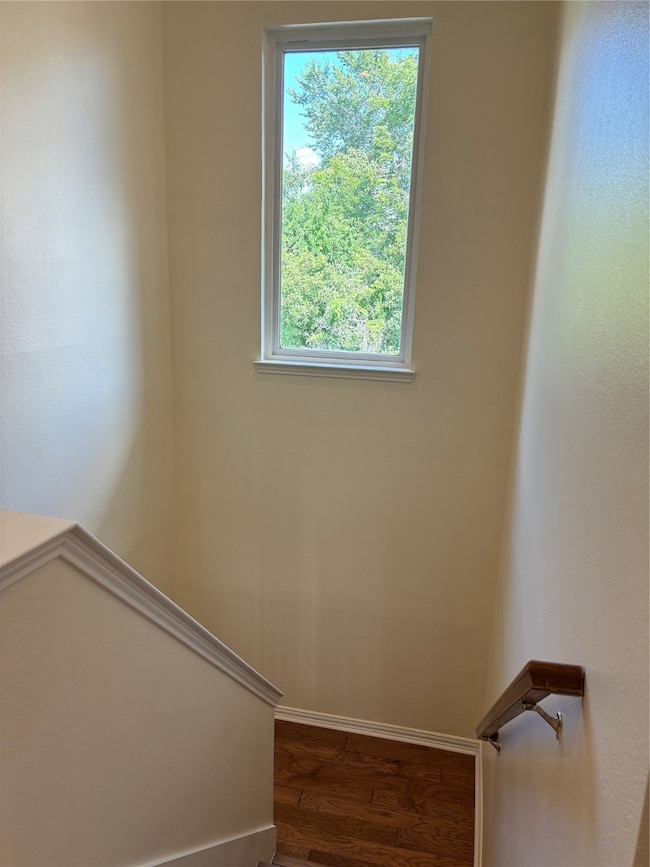 Stairs featuring wood finished floors and healthy amount of natural light