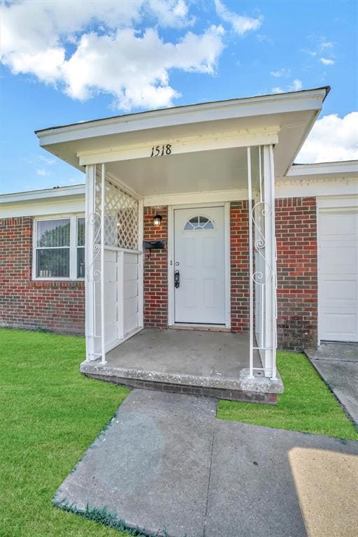 Property entrance with brick siding and a lawn