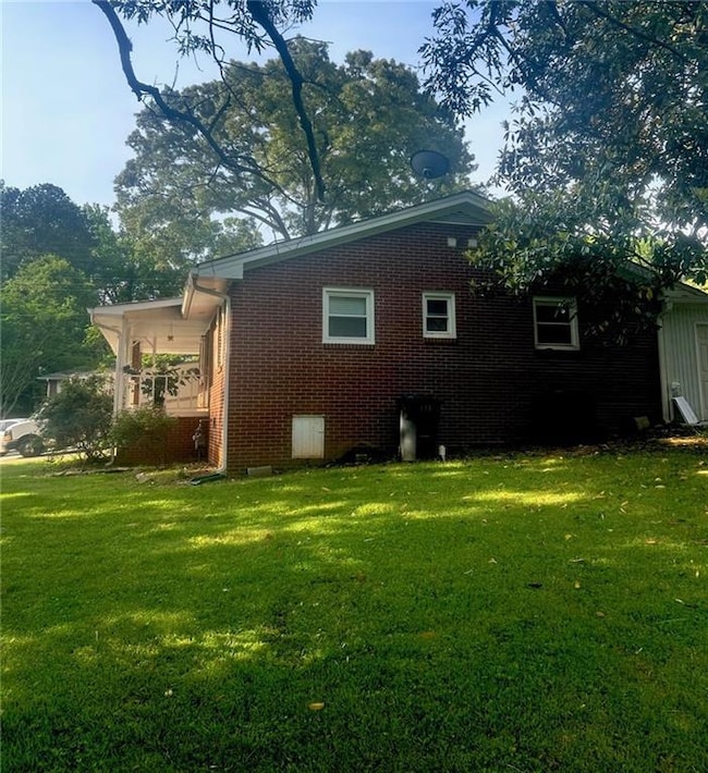 Back of property featuring a lawn and brick siding
