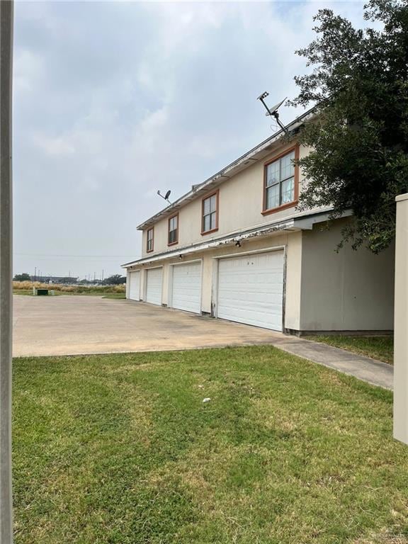 View of front facade with a front lawn, driveway, stucco siding, and an attached garage