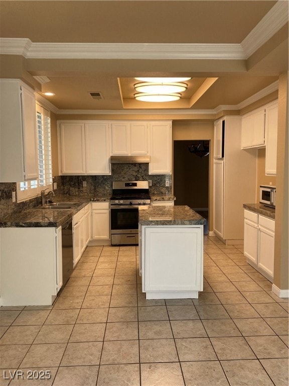 Kitchen with white cabinets, tasteful backsplash, stainless steel stove, light tile patterned flooring, and ornamental molding
